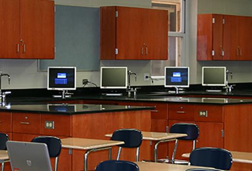 Science classroom interior with cherry wood cabinets, computers, and student desks.
