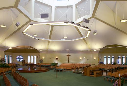 Interior worship space with wooden pews, green carpet, and octagonal skylight.