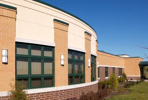 An arched, yellow brick exterior with dark green trim around windows.