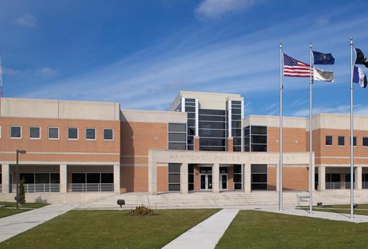 The exterior of a brick building. City, State and American flag blowing in breeze. Bright blue sky  