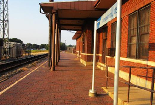 The exterior of the passenger station shows signage and a brick walkway.