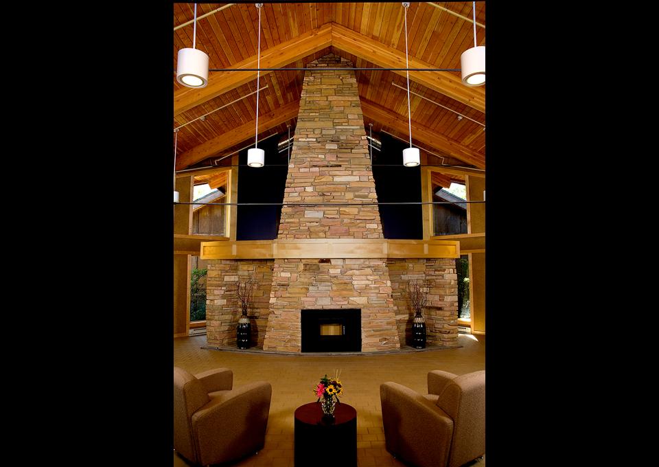 A tall stone fireplace. Wood plank ceiling.