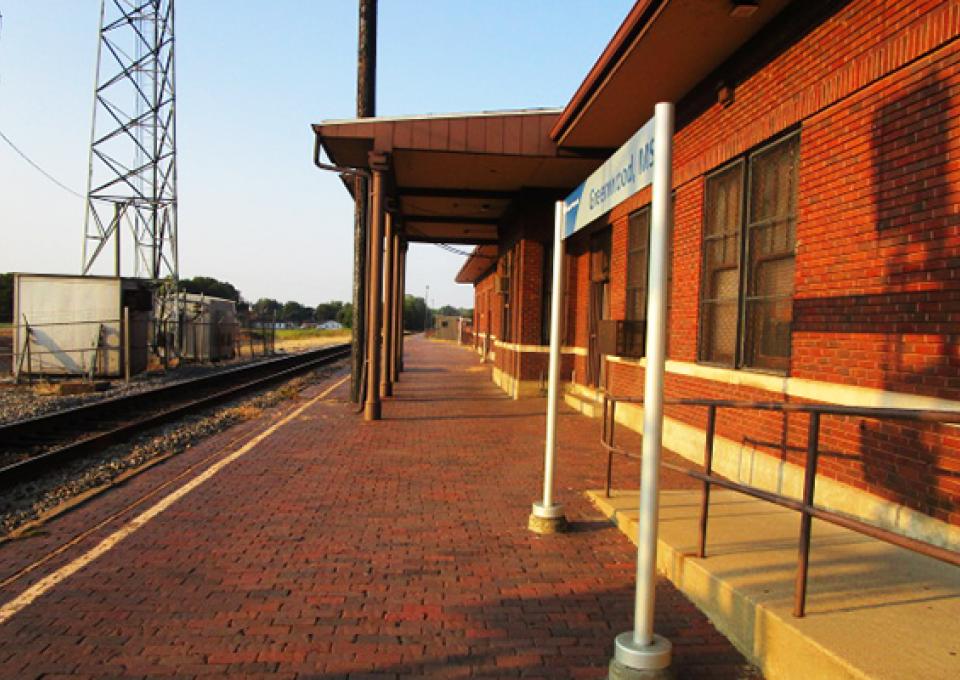 The exterior of the passenger station shows signage and a brick walkway.