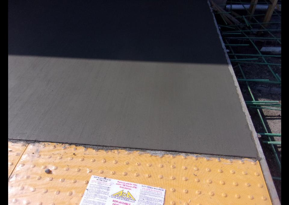 The wet concrete of the new platform is detailed. ADA striping showed in yellow.
