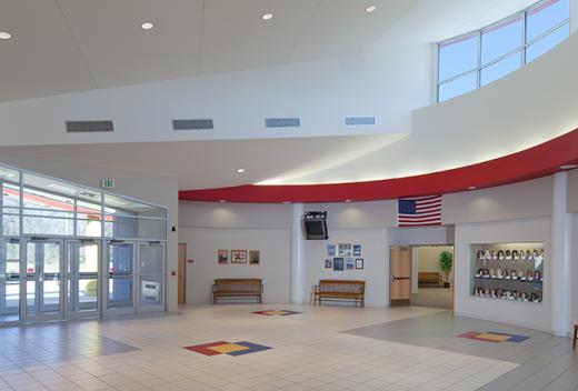 School interior atrium with a circular ceiling. Floor accents in red, yellow, and blue colors.