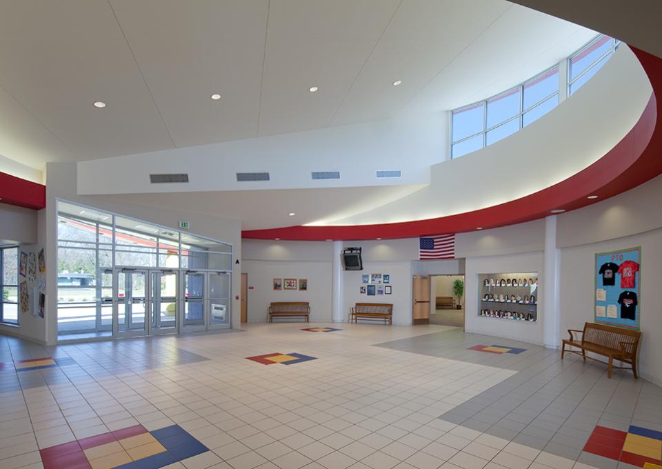 School interior atrium with a circular ceiling. Floor accents in red, yellow, and blue colors.