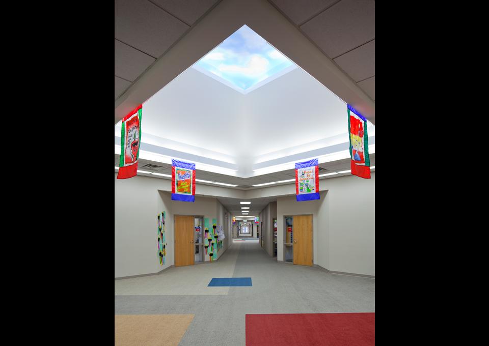School interior hallway to classrooms with dramatic skylight.