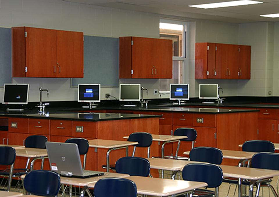 Science classroom interior with cherry wood cabinets, computers, and student desks.