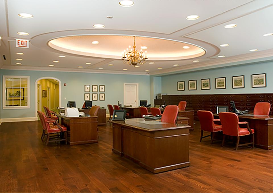 Bank interior office space with cherry furniture and flooring and a circular tray ceiling.