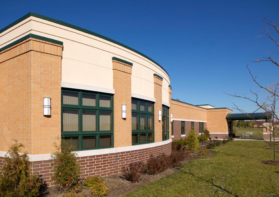 An arched, yellow brick exterior with dark green trim around windows.