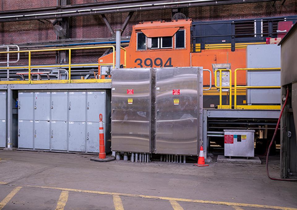 Interior maintenance building with a view of electrical panel and locomotive car.