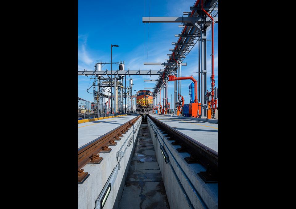 Fueling and maintenance track with locomotive car in distance.
