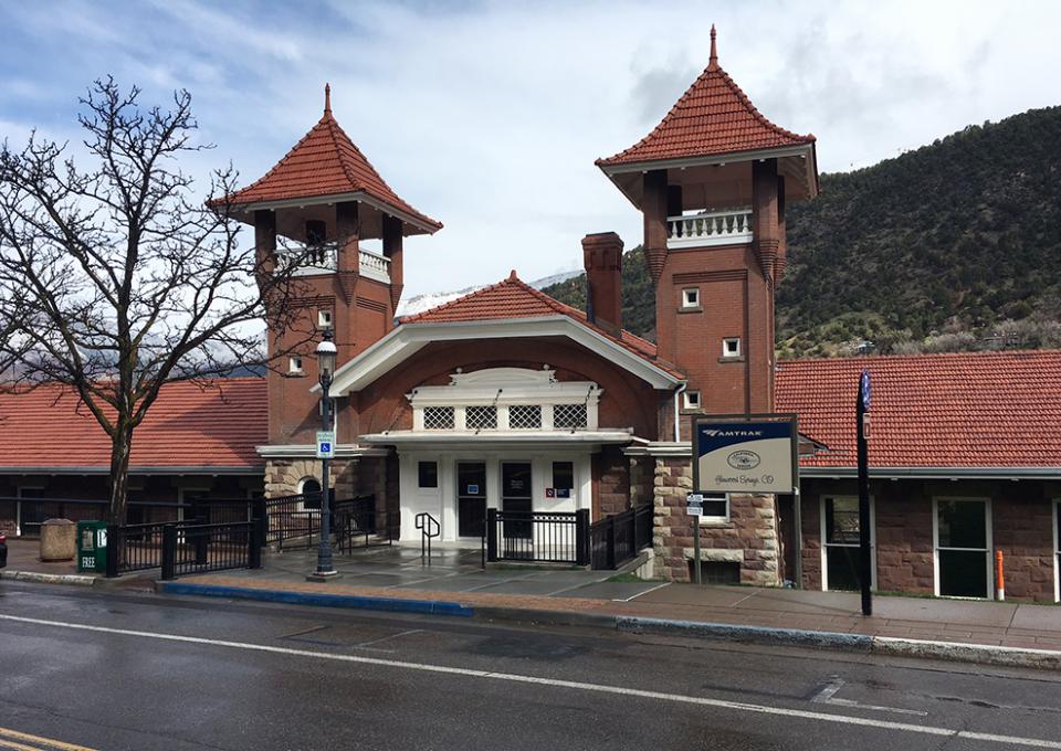 Red tile roof, brick, and sandstone passenger station.